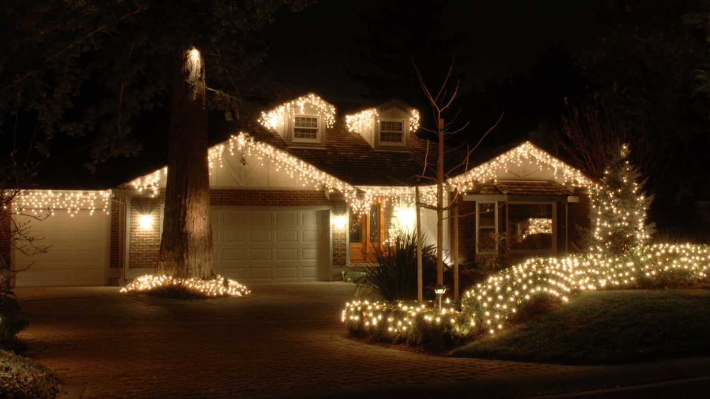 Icicle lights along the gables and lit shrubs at night