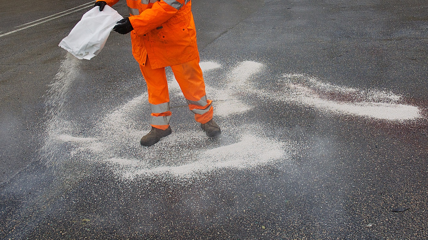 Crew member spreading salt on pavement