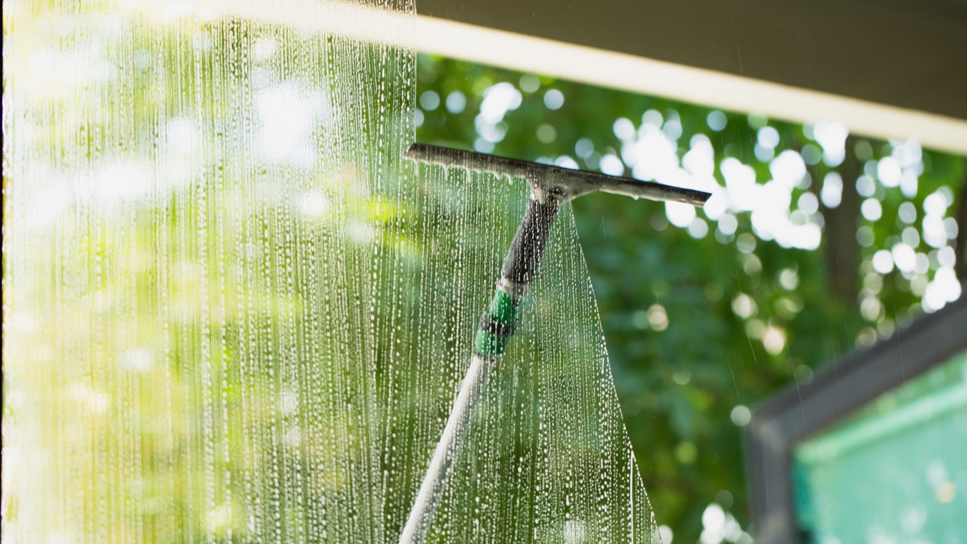 Squeegee on a pole clearing a soapy window