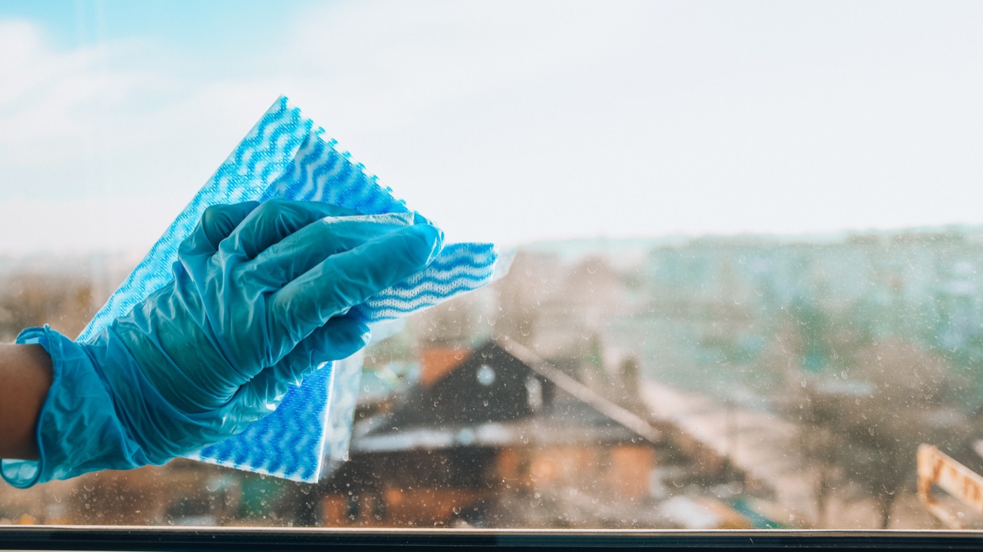 Gloved hand wiping a window clean